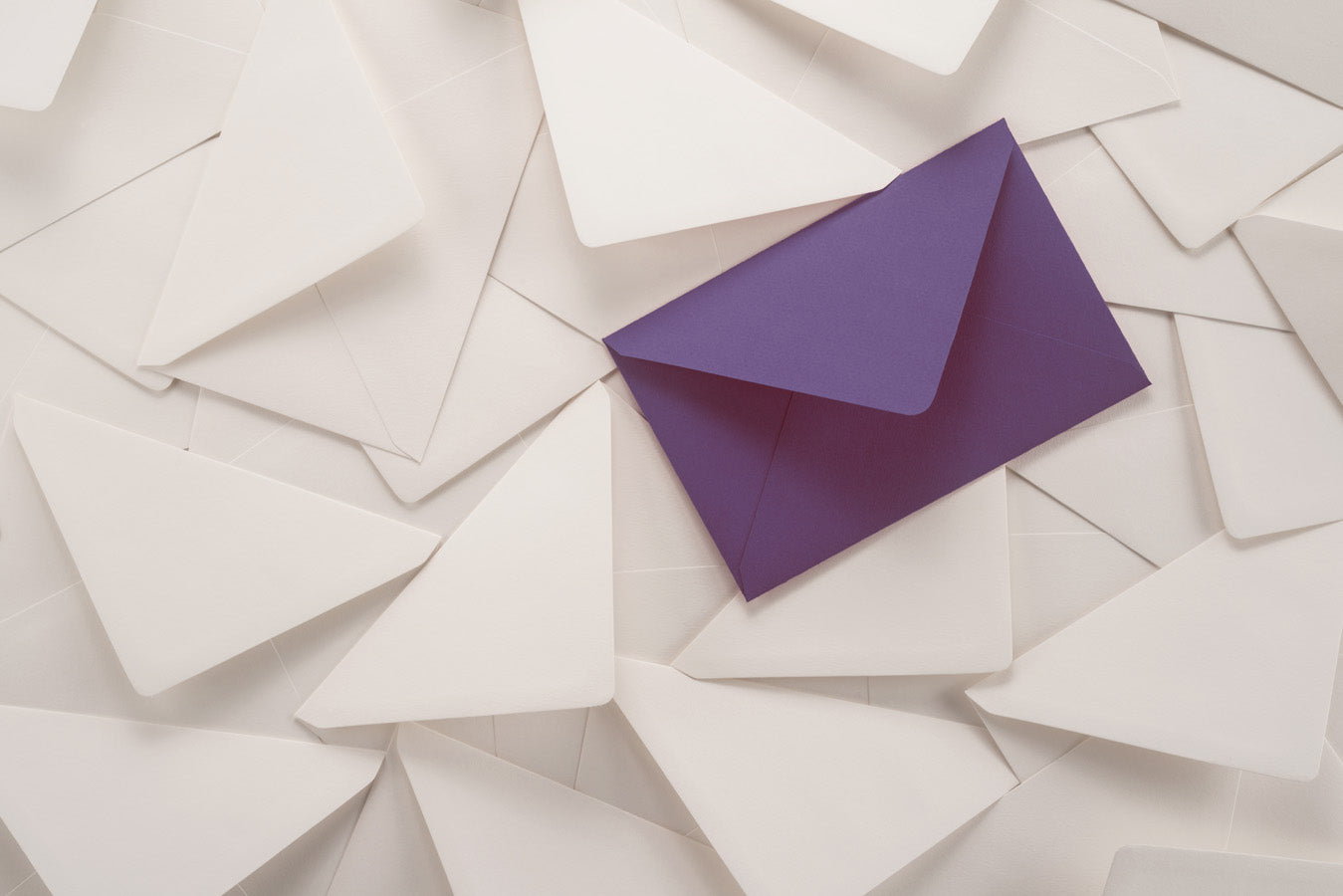 Purple envelope on pile of white envelopes (licensed from Adobe Stock Photos)