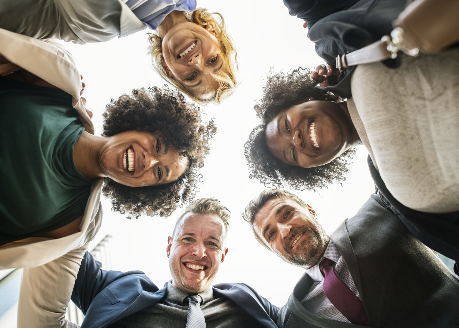 5 smiling team members in huddle (licensed from PhotoDune)