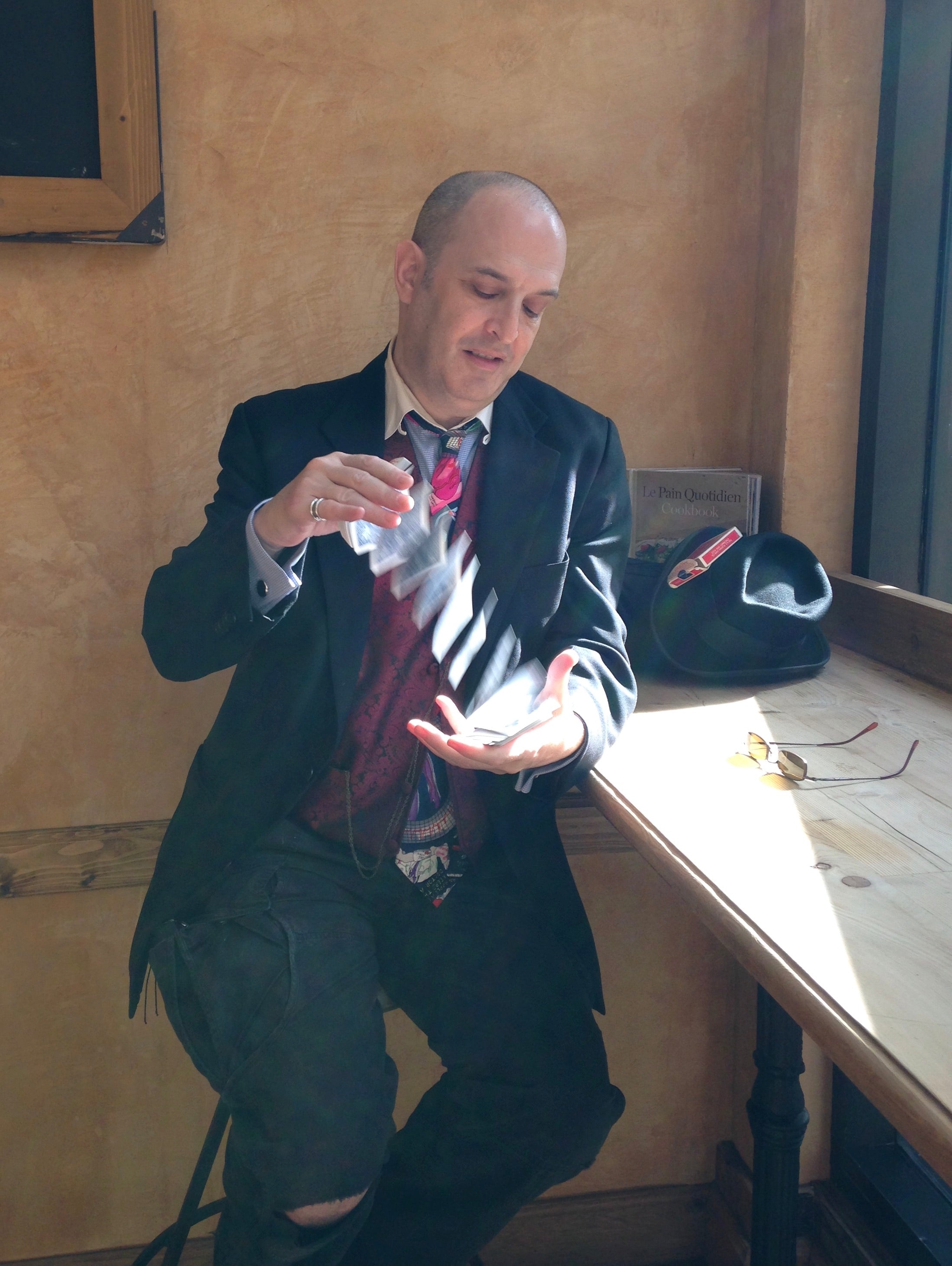 Magician Ben Robinson cascading a deck of cards in a ray of sunlight