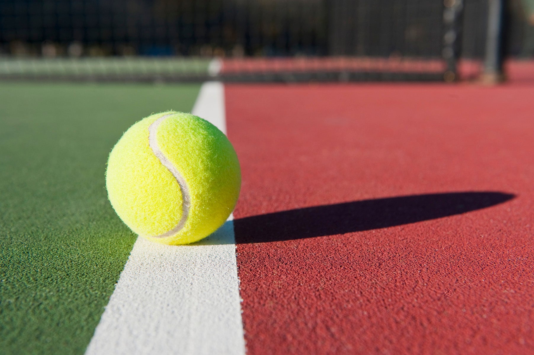 Tennis ball sitting on boundary line (licensed from PhotoDune)